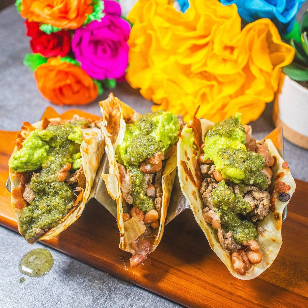 three tacos with colorfulpaper flowers in the background